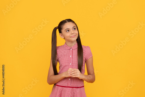 Dreamful school age girl child with pensive look fantasize about something yellow background, dreamer