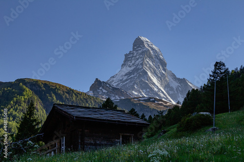 View of iconic Matterhorn snowcapped summit from Zermatt with typical houses and trails, Valais, Swiss Alps, Switzerland