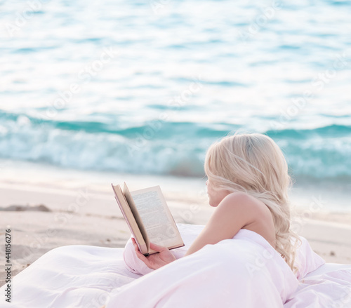 Relax concept. Cozy and comfortable bed near the sea. Summer vacations still life. Woman reading a book.