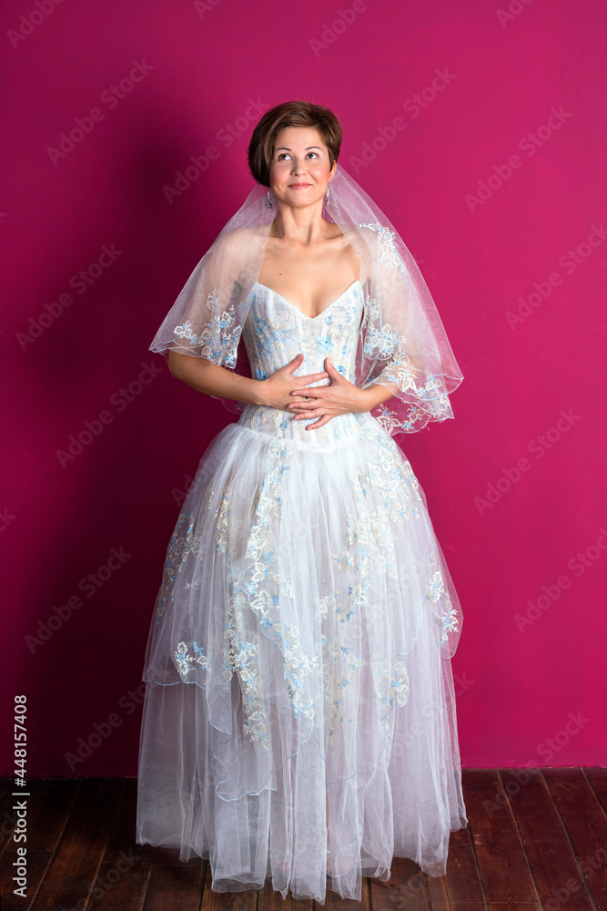 Fototapeta premium Bride on pink background. Woman dressed in wedding dress with lace, copyspace for text