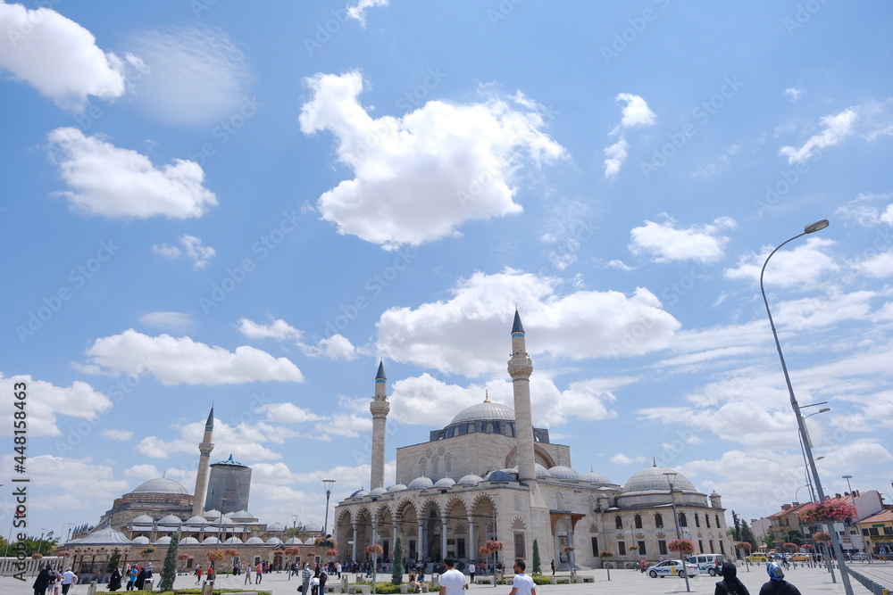 Sultan Selim Mosque (cami) and Mevlana tomb (trbe) in Konya, Turkey and beautiful and colorful flowers and many people and tourists  with blue and cloudy sky backgrounds.24.07.2021. Konya. Turkey
