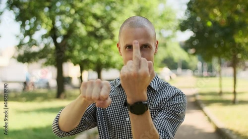 Bald bearded man showing middle finger. a person shows a rude gesture rejecting any communication. male smiling in camera and shows rude sign of disrespect, making a fuck gesture. photo