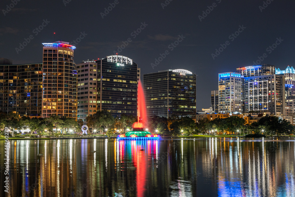 Nightime photo of Lake Eola in downtown Orlando with the colorful fountain and reflections on the water