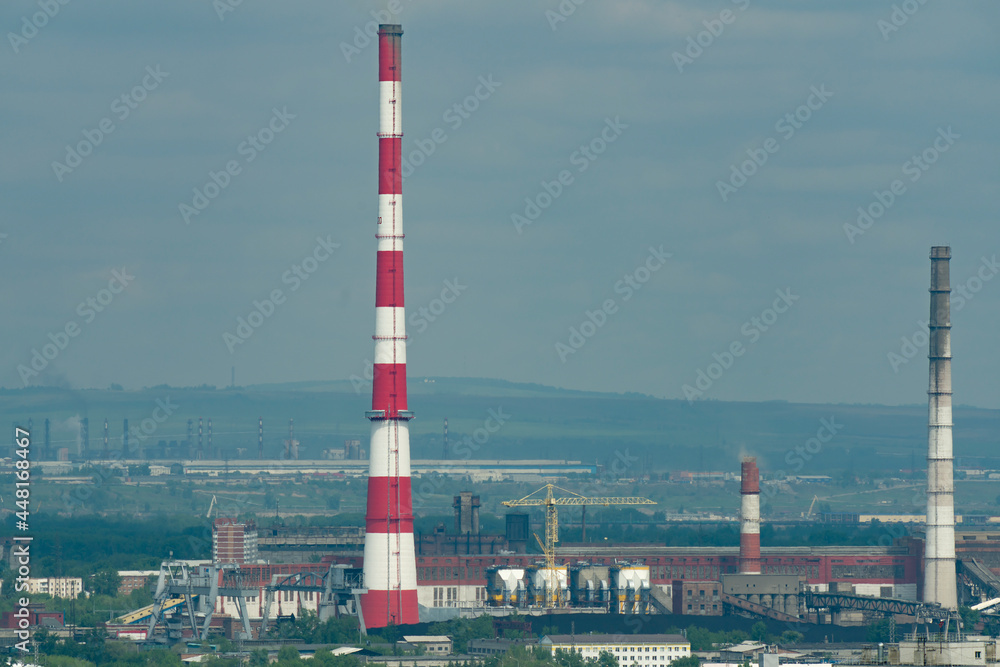 A huge red-white brick chimney in the center of an industrial city.