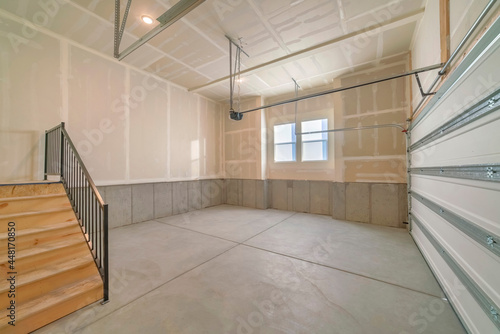 Empty garage interior with wooden stairs and windows