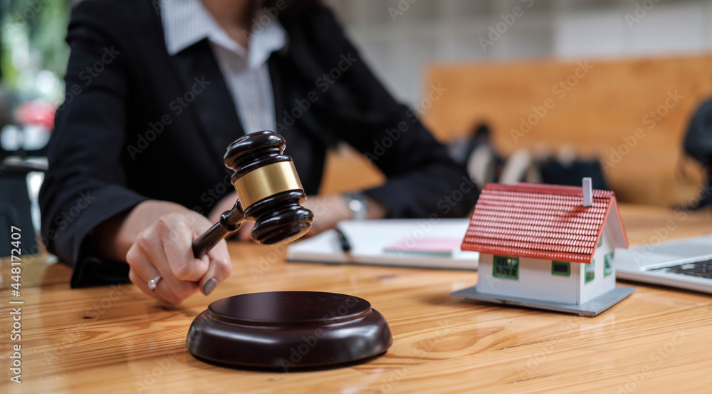 Real Estate Law concept. Gavel on sounding block in hand's female judge at a courtroom, working for the insurance compensations. report the case on table Real Estate Law concept. Gavel on sounding block in hand's female judge at a courtroom, working for the insurance compensations. report the case on table