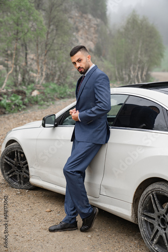 attractive man in business suit stands at the car