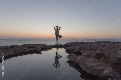 Young man practicing yoga at Sunset in Can Marroig in Formentera, Spain