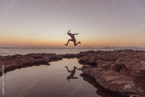 Young man jump the Sunset in Can Marroig in Formentera, Spain
