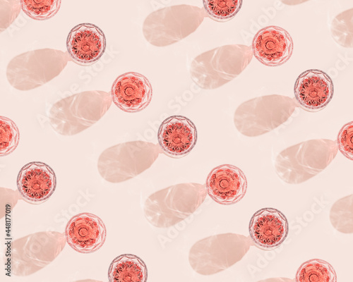 Summer alcohol drink pattern with glass of rose sparkling wine top view, dark shadows on pastel pink background.
