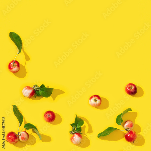 Pattern from small red apples and green leaves with dark shadows