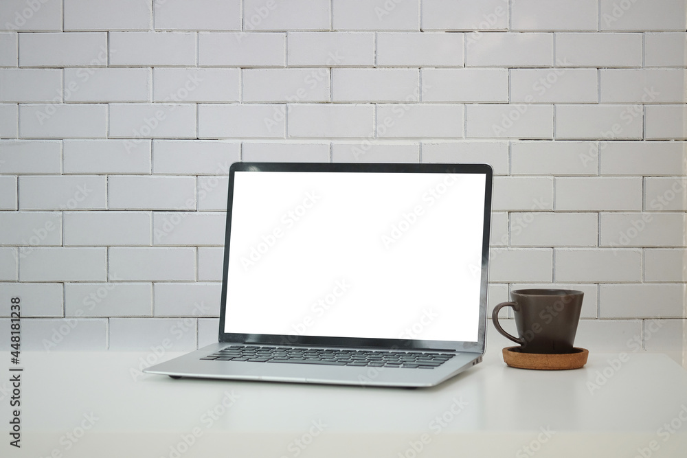 Laptop computer with blank screen and coffee cup on white table with brick wall. Laptop computer with blank screen and coffee cup on white table with brick wall.