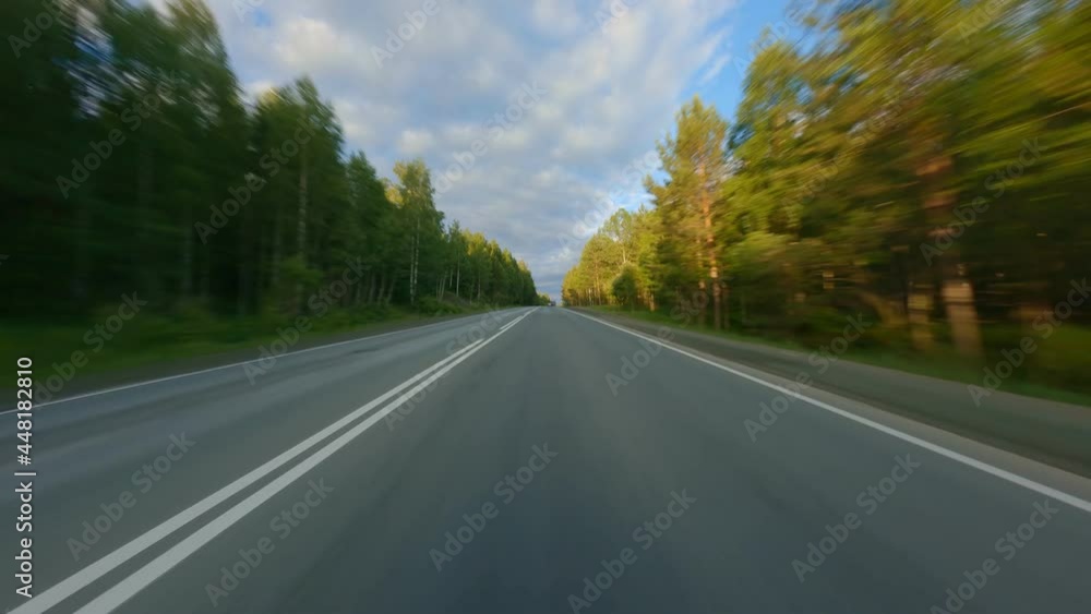 The highway passes through a dense forest. The crowns of tall trees are illuminated by the rays of the sun, a day trip. Tables with signs are located along the road. High quality. 4k footage. The highway passes through a dense forest. The crowns of tall trees are illuminated by the rays of the sun, a day trip. Tables with signs are located along the road. High quality. 4k footage.