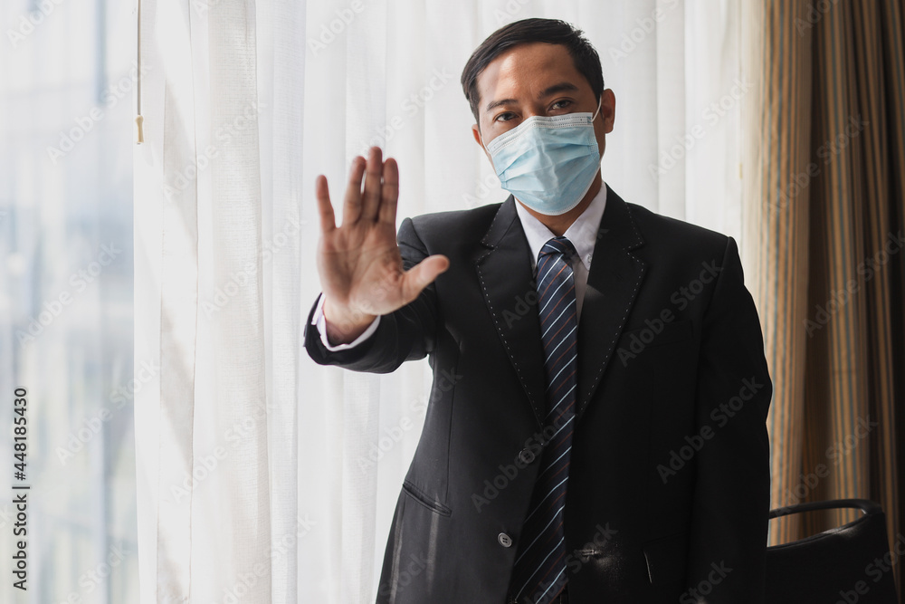 Businessman in medical mask wearing black suit and tie standing with stop gesture hand Businessman in medical mask wearing black suit and tie standing with stop gesture hand