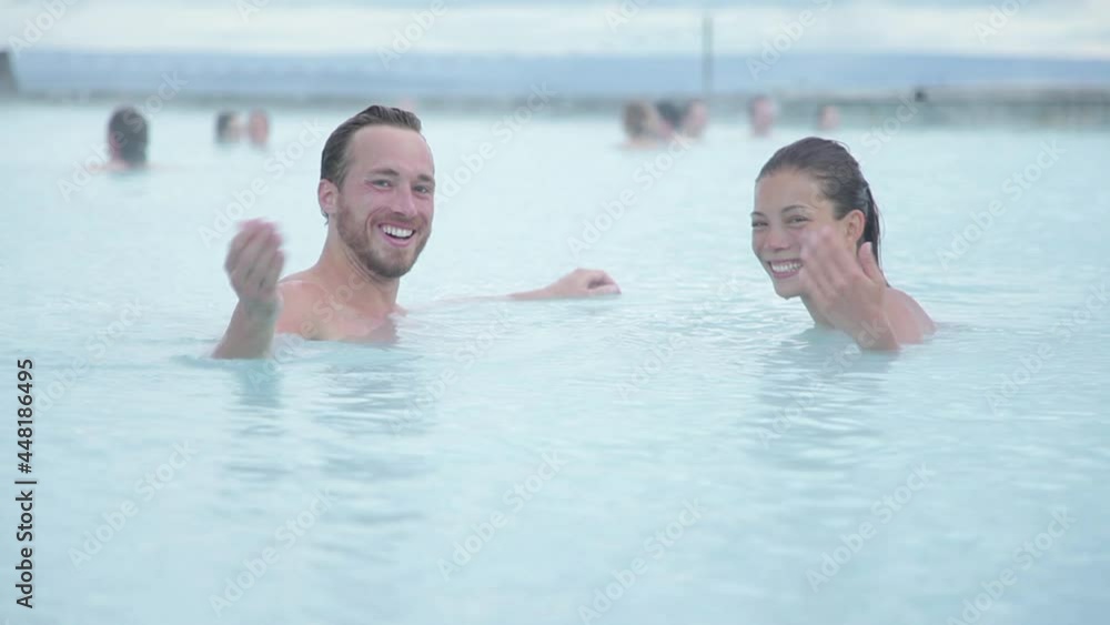 Iceland travel. Hot spring geothermal spa. Couple inviting you to join them waving hand welcoming. Romantic couple in love relaxing in hot pool on Iceland Iceland travel. Hot spring geothermal spa. Couple inviting you to join them waving hand welcoming. Romantic couple in love relaxing in hot pool on Iceland