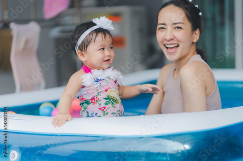 Selective focus baby girl and blur mom in swimming pool with smile happy and relax time