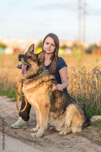 Beautiful young girl with a shepherd dog on the field. © shymar27