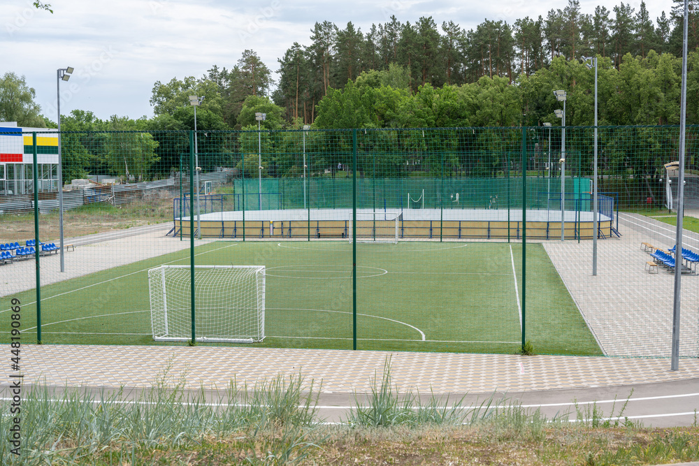 Fototapeta premium Green soccer field with blue seats. Sports stadium.
