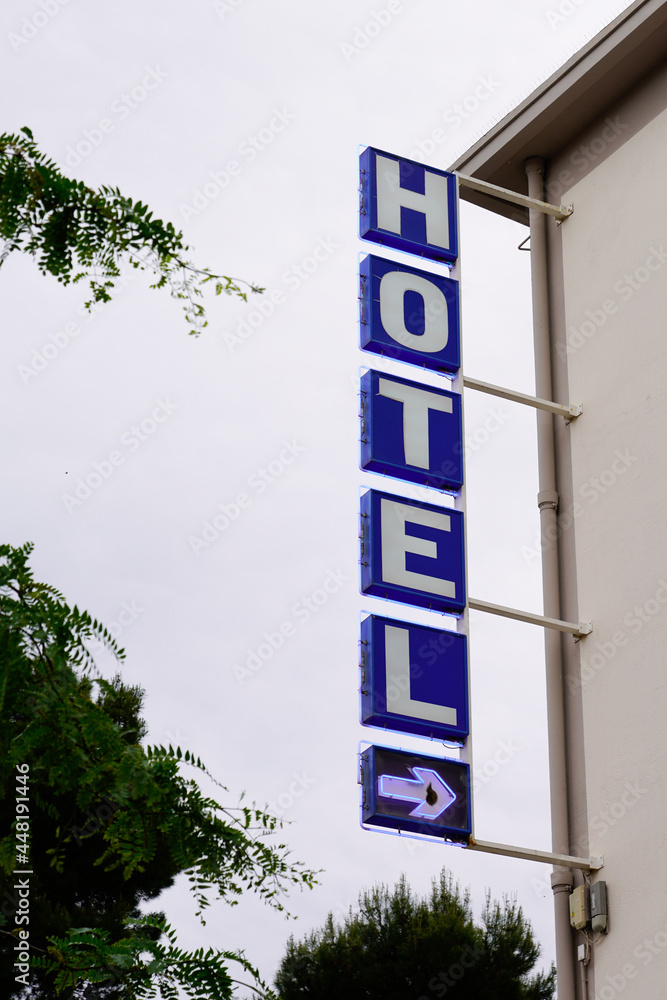 Hotel sign text blue and arrow in wall building facade in french tourist city Hotel sign text blue and arrow in wall building facade in french tourist city