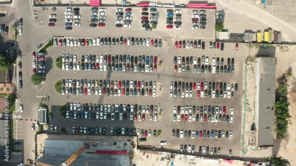 car parking lot free of charge aerial view. Overhead aerial of a car trying to find a parking spot in a busy parking lot. Aerial top view of many cars parked. car parking lot free of charge aerial view. Overhead aerial of a car trying to find a parking spot in a busy parking lot. Aerial top view of many cars parked.