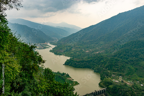 mountain valley with cloudy sky and river leading at morning from flat angle