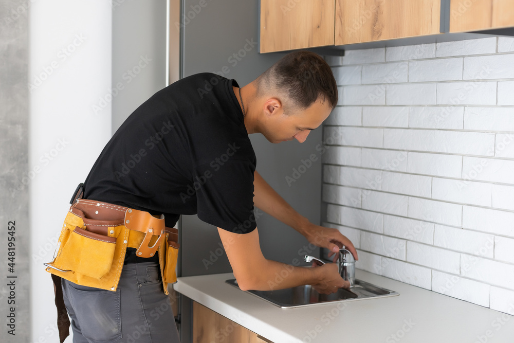 Man installing the kitchen tap and the sink Man installing the kitchen tap and the sink