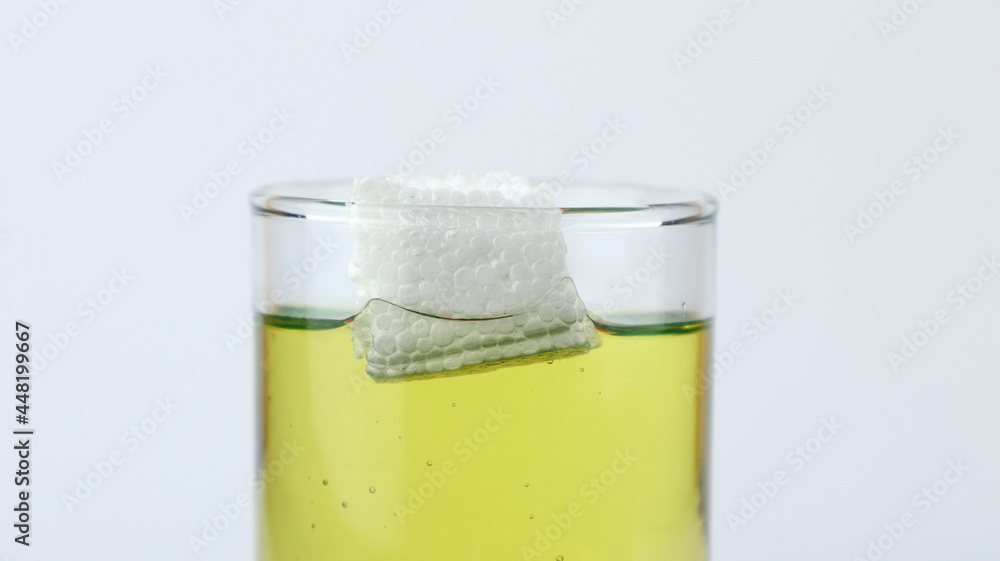 Styrofoam floats on olive oil, demonstration of density experiment with liquid. The science concept of density Styrofoam floats on olive oil, demonstration of density experiment with liquid. The science concept of density
