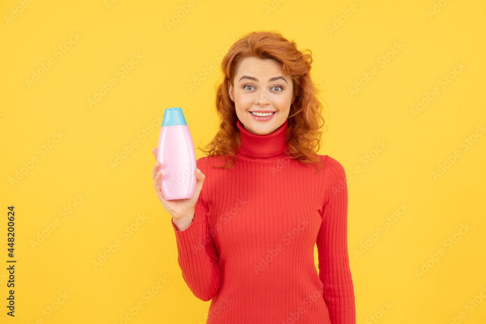 charming redhead woman face portrait holding shampoo bottle on yellow background, haircare charming redhead woman face portrait holding shampoo bottle on yellow background, haircare