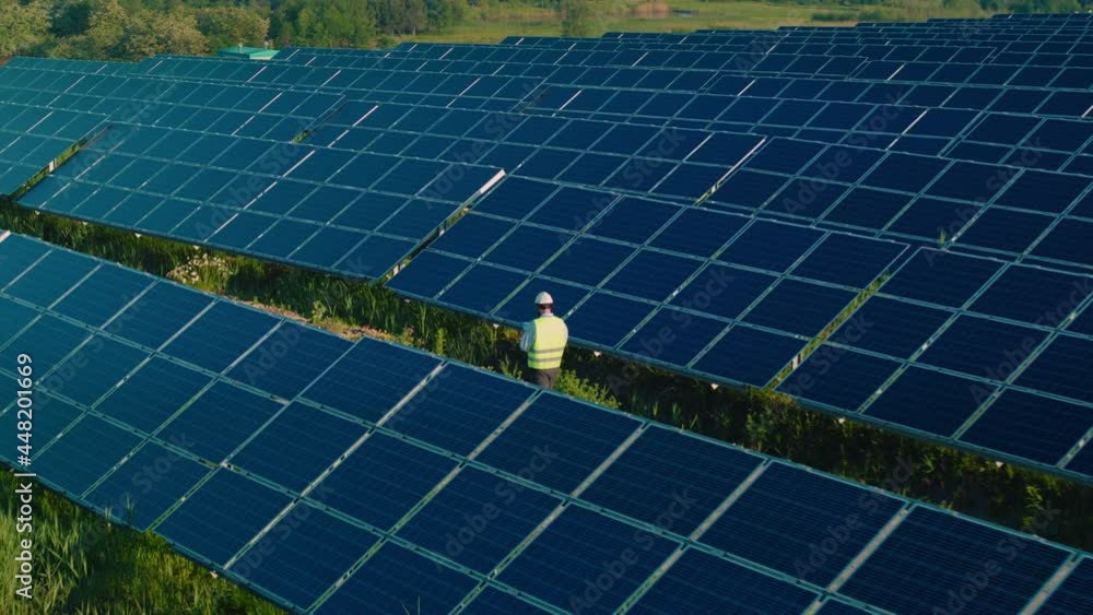 Man in workwear walking on field with solar panels Man in workwear walking on field with solar panels