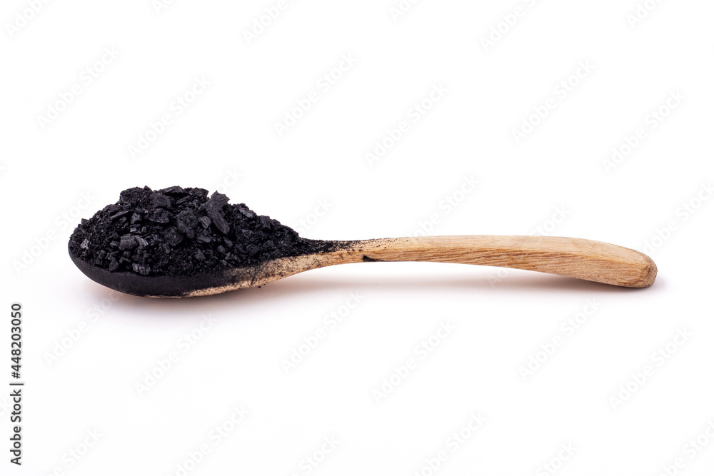 Side view of Small pieces and powder of charcoal was placed on a wooden spoon isolated on a white background. Side view of Small pieces and powder of charcoal was placed on a wooden spoon isolated on a white background.