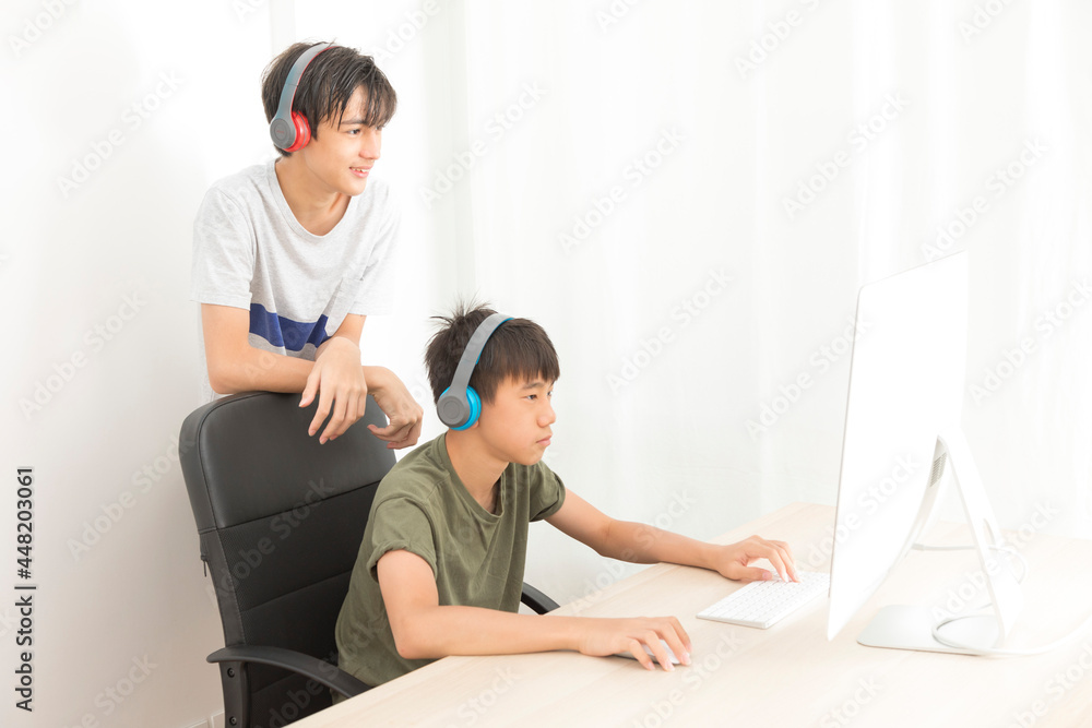 Two multiethnic teenage boys with headphone have fun with computer games at home. Two multiethnic teenage boys with headphone have fun with computer games at home.