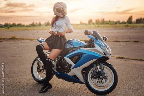 Female motorcyclist and modern motorbike on country road © Fxquadro