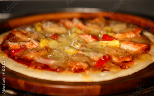 Background, Selective focus and close up on tasty homemade seafood pizza with shrimp, pineapples, crab sticks on wooden tray. Food Concept.