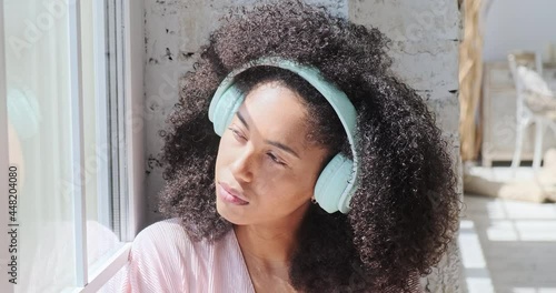 A gorgeous mixed-race woman is captivated by the pleasant sensations as she listens to relaxing music on her phone. A break from freelance work, as well as a search for inspiration and creativity photo