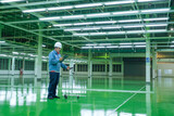 Electrical inspector engineer using lux meter for testing illuminance lighting of production line at the industrial factory