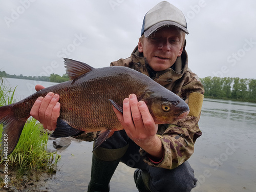 Fototapeta Naklejka Na Ścianę i Meble -  Happy fisherman holding a beautiful common bream.