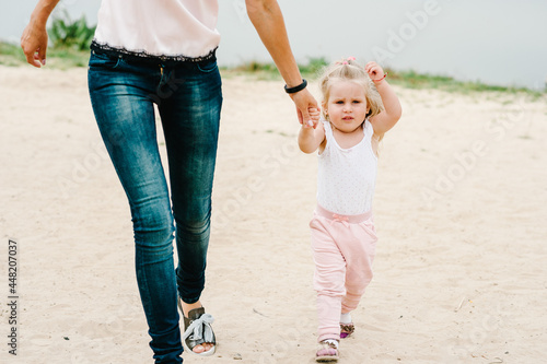 Mom with daughter running on the beach. Girl and mother walk on the seaside in the summer. Happy family near the park on holidays. © Serhii