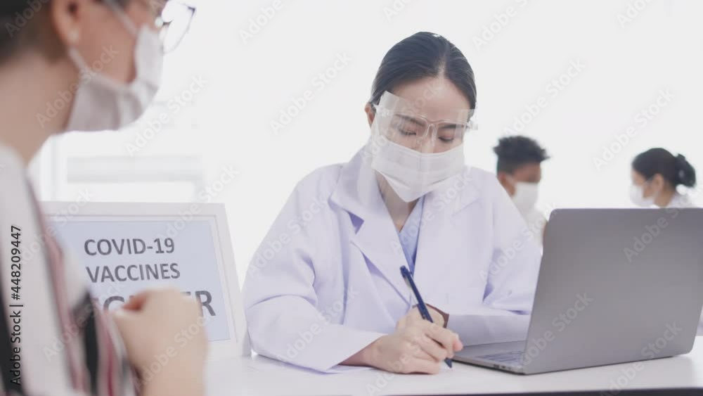 Asian doctor records patients treatment information on paper and laptop for hospital treatment. Wear face mask to prevent spread of COVID-19. Social Security insurance for medical treatment Asian doctor records patients treatment information on paper and laptop for hospital treatment. Wear face mask to prevent spread of COVID-19. Social Security insurance for medical treatment
