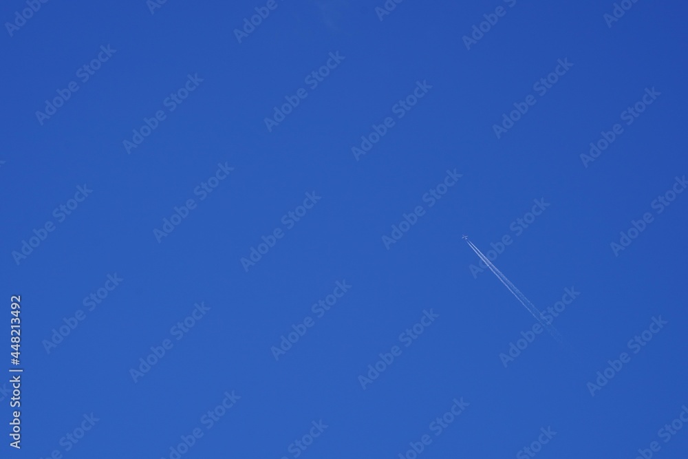 Airplane flying high up and leaving white traces or contrail behind. There is a lot of copy space on the blue sky on the background. Airplane flying high up and leaving white traces or contrail behind. There is a lot of copy space on the blue sky on the background.