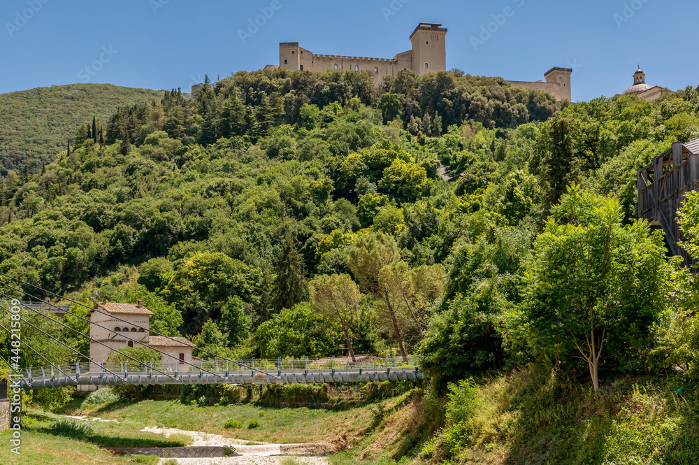 The pedestrian bridge over the dry Tessino stream with the Albornoziana fortress overlooking the hill of Spoleto, Italy
