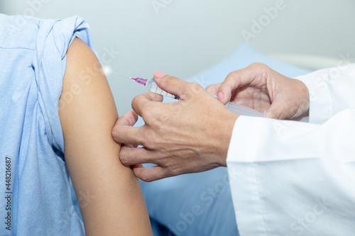Doctor giving patient vaccine  COVID-19  flu or influenza shot. Vaccination and prevention against flu  Covid-19 virus pandemic with syringe at hospital room.