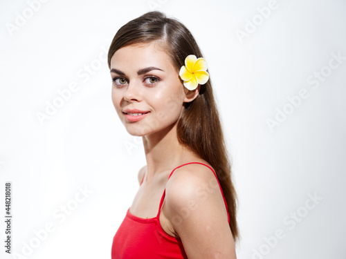 brunette woman with yellow flower in her hair and red t-shirt light background