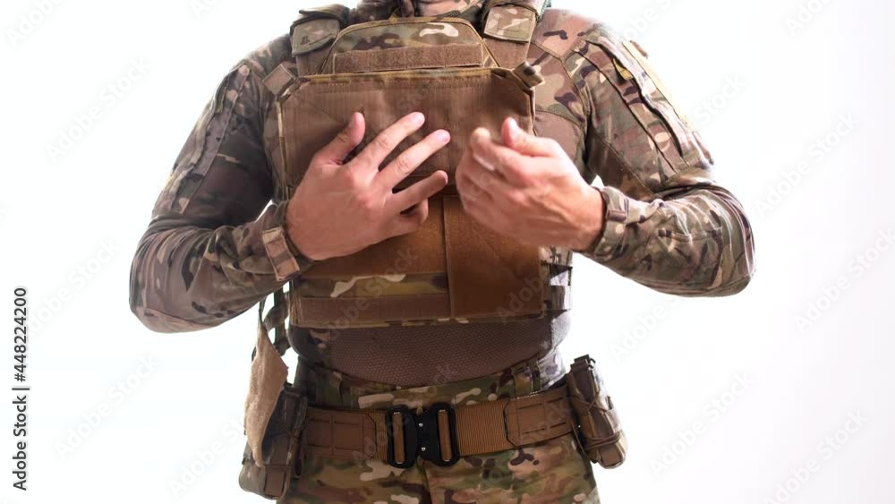 Man in combat camouflage removes his body armor on a white background. Isolated Man in combat camouflage removes his body armor on a white background. Isolated