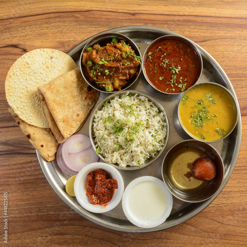 Veg Thali from an indian cuisine, food platter consists variety of veggies,paneer dish, lentils, jeera rice,roti, sweet dish, curd, onion etc., selective focus photo