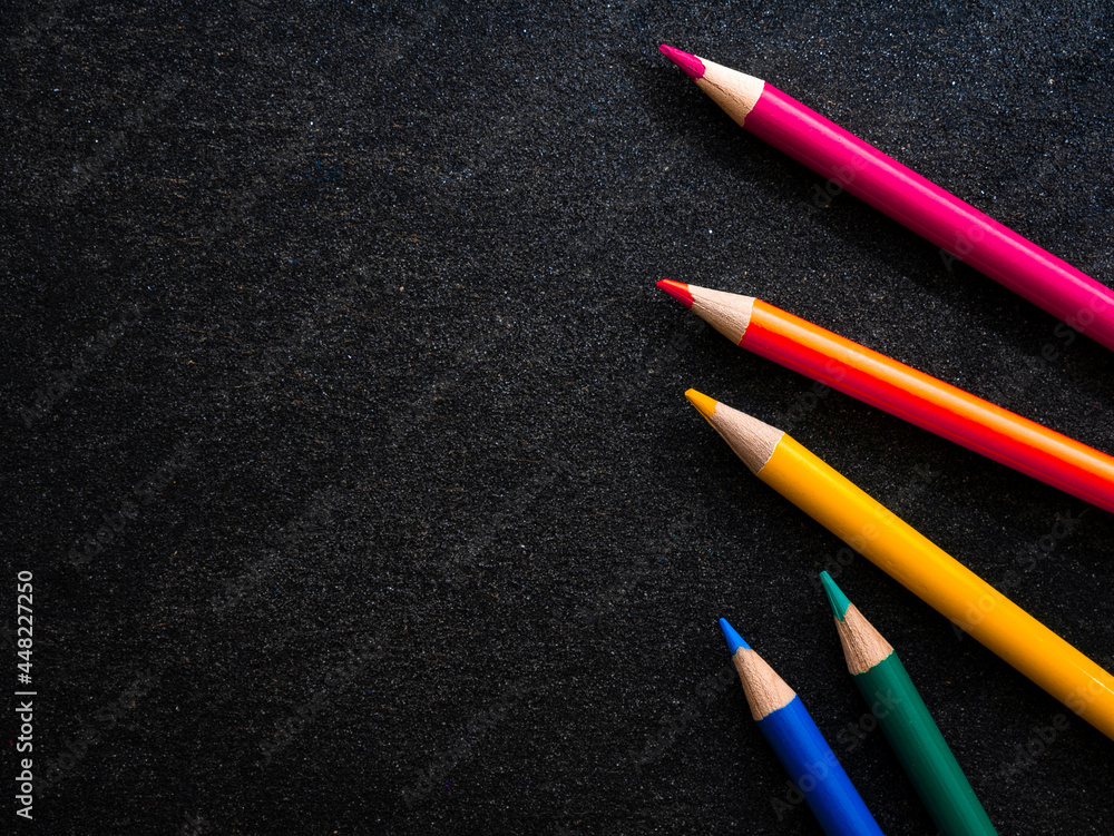 Bright colored pencils on a dark black background. Seven colors of the rainbow. Back to school. Education and creativity. Drawing and art. Free space for text. Bright colored pencils on a dark black background. Seven colors of the rainbow. Back to school. Education and creativity. Drawing and art. Free space for text.