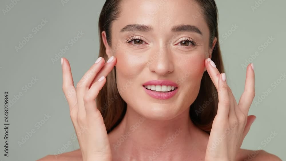 Beautiful Young Woman with Clean Fresh Skin standing over light grey background Beautiful Young Woman with Clean Fresh Skin standing over light grey background