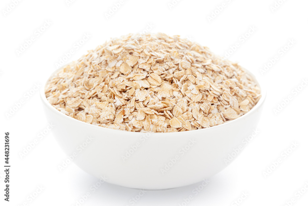 Close-up of dry organic whole rolled oats (Avena sativa) in a white ceramic bowl over white background Close-up of dry organic whole rolled oats (Avena sativa) in a white ceramic bowl over white background