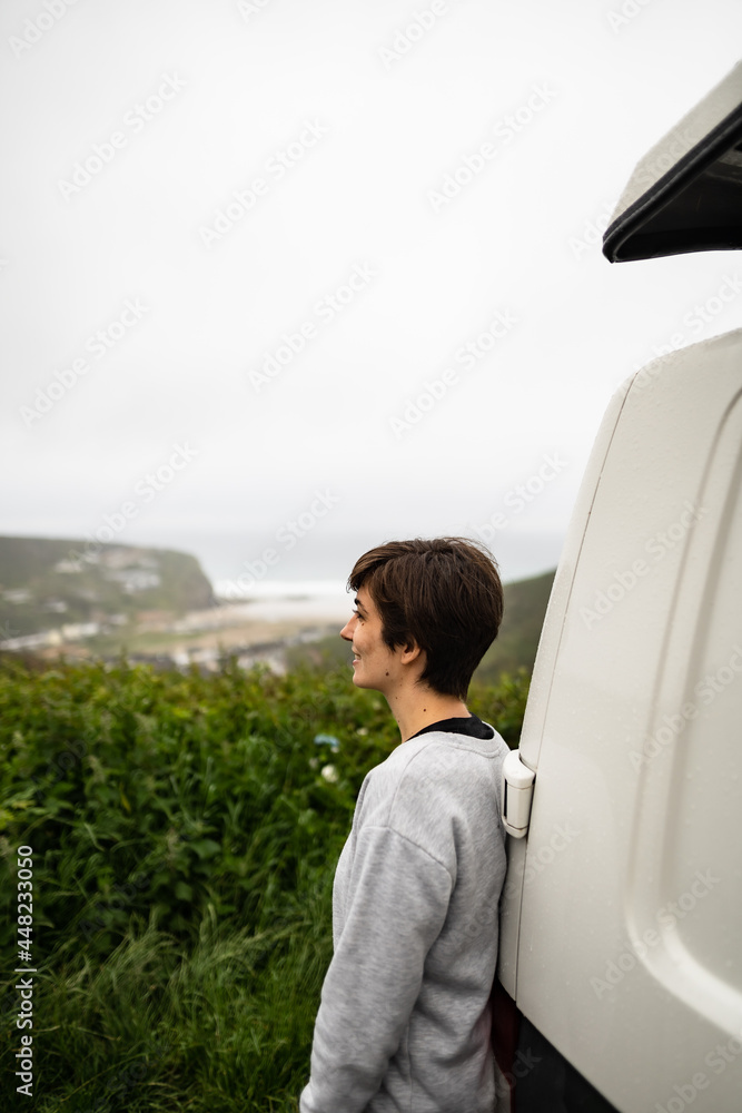 Attractive young female located next to her campervan while enjoying morning fresh air