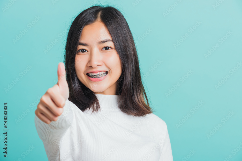 Young beautiful Asian woman cheerful smiling showing finger thumb up, Portrait happy female using showing like the gesture for good sign, studio shot isolated on a blue background Young beautiful Asian woman cheerful smiling showing finger thumb up, Portrait happy female using showing like the gesture for good sign, studio shot isolated on a blue background