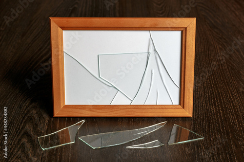 Wooden photo frame with broken glass on the table.